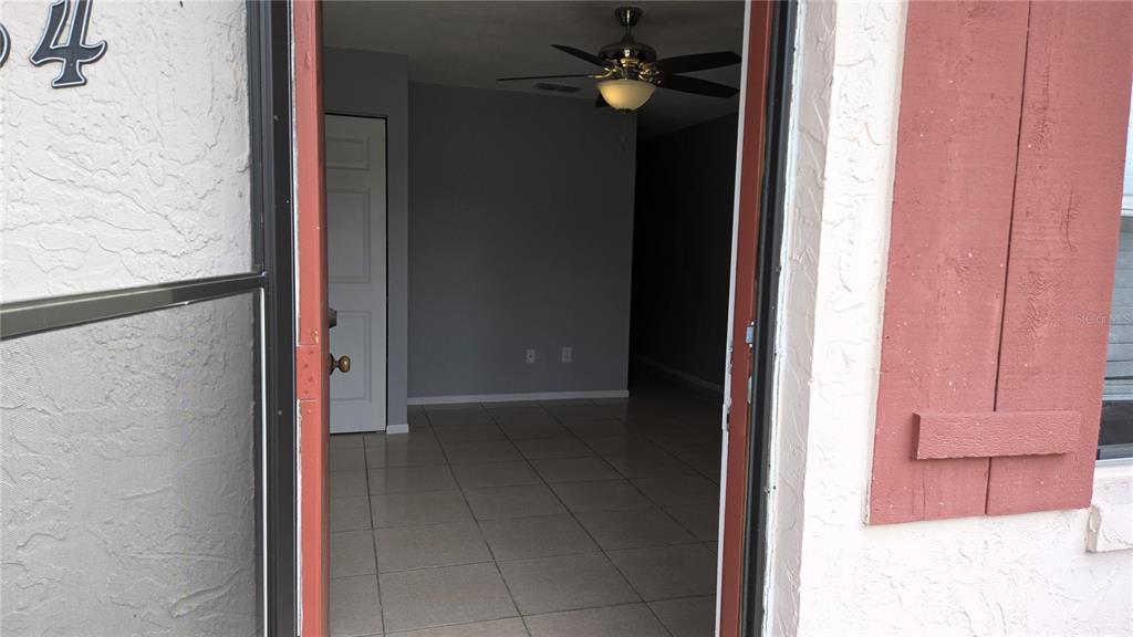 A view through an open front door into a tiled living area with a ceiling fan — 54 W MARBRISA WAY, KISSIMMEE, FL