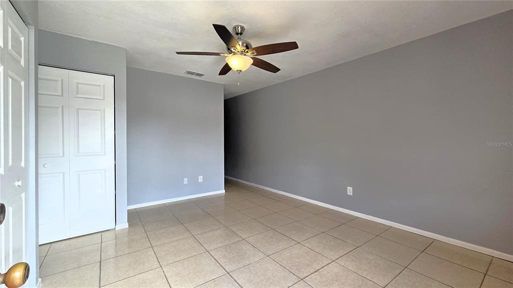 An empty room features gray walls, light-colored tile flooring, and a ceiling fan — 54 W MARBRISA WAY, KISSIMMEE, FL