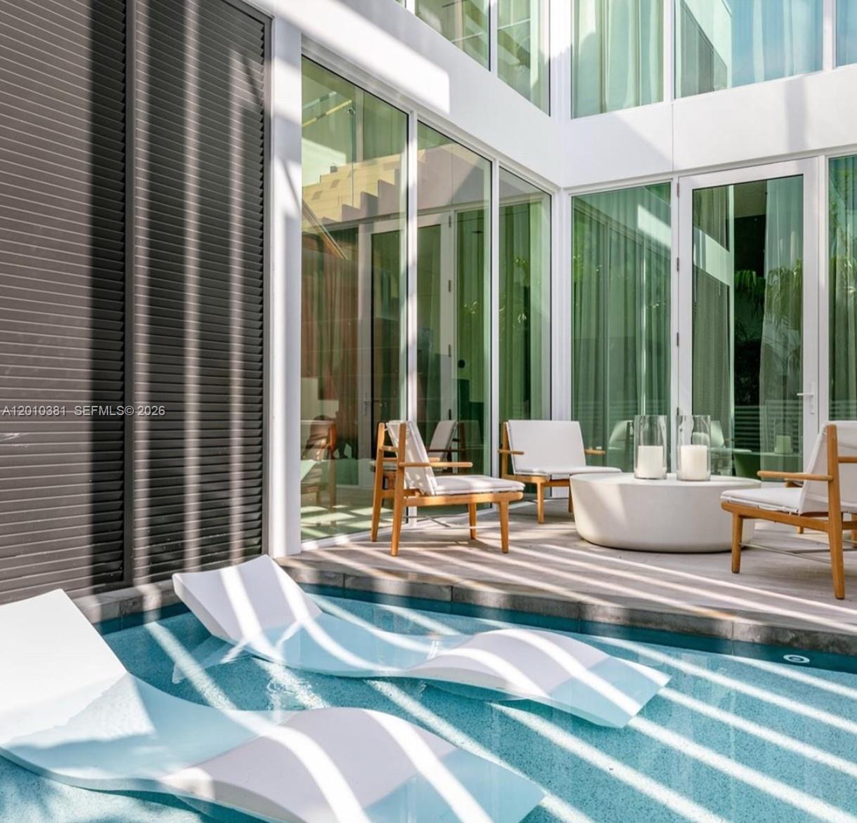A modern patio features a swimming pool with lounge chairs and outdoor seating area — 1081 W 48th St # N01, Miami Beach FL 33140, MIAMI BEACH, FL