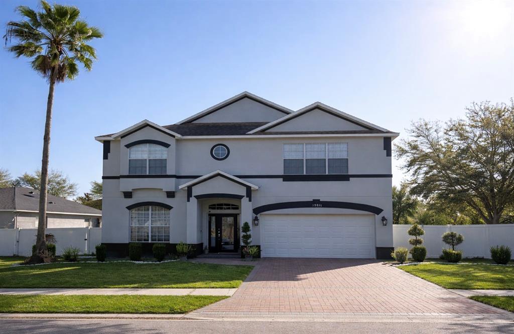 A two-story house with a paved driveway, a palm tree, and a white fence — 13851 AMBERLEIGH ROAD, ORLANDO, FL