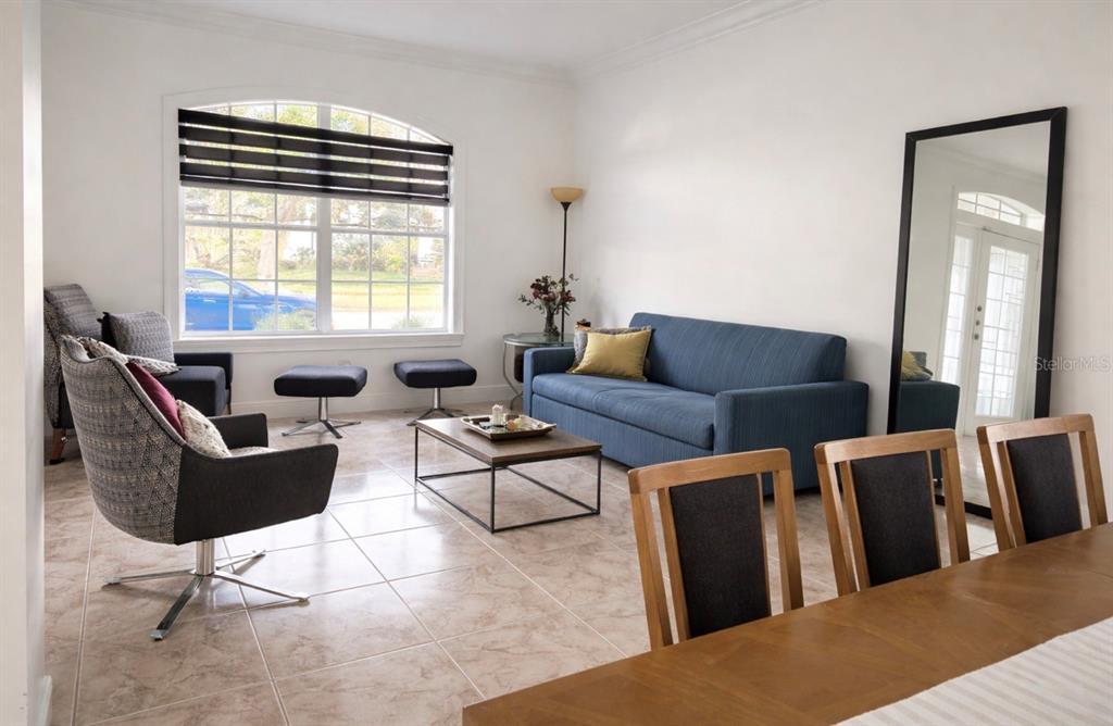 A living room with tile floors, a blue sofa, armchairs, and a large floor mirror — 13851 AMBERLEIGH ROAD, ORLANDO, FL