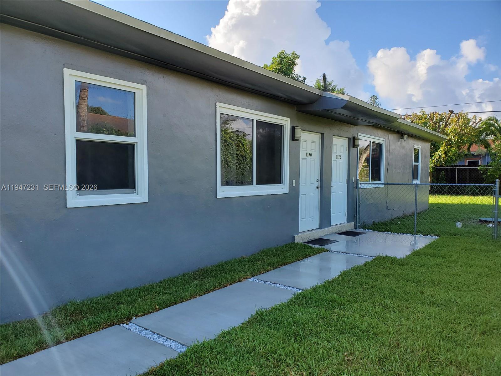 A gray exterior wall features two white doors, windows, and a concrete walkway — 1170 NE 111th St # 1170, Miami FL 33161, MIAMI, FL