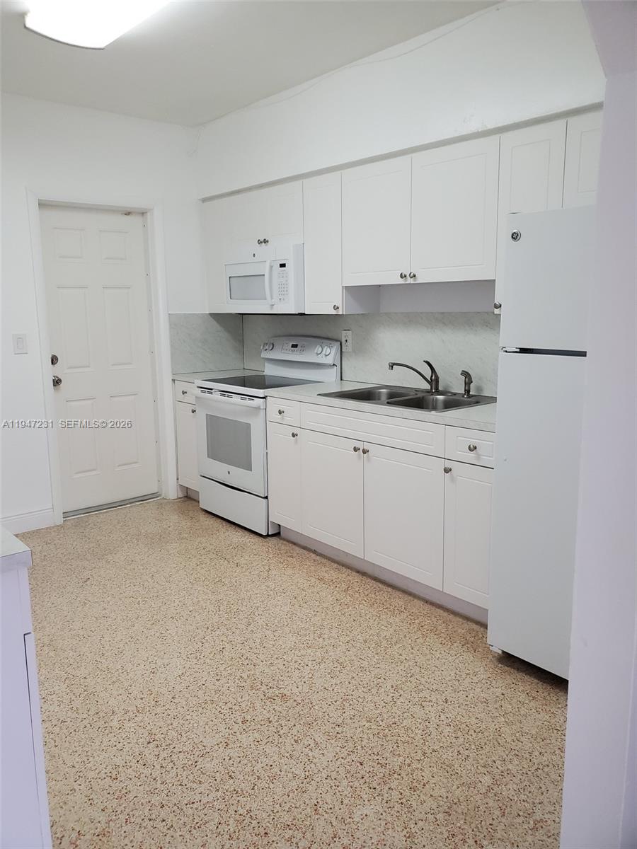 A kitchen features white cabinets, white appliances, a double sink, and speckled flooring — 1170 NE 111th St # 1170, Miami FL 33161, MIAMI, FL