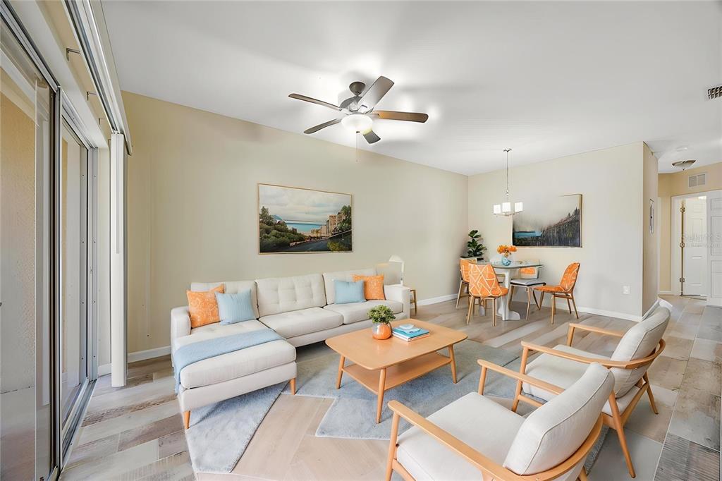 A living and dining area features a sectional sofa, two armchairs, and light wood flooring — 1231 GODAVARI WAY E UNIT 202, WESLEY CHAPEL, FL