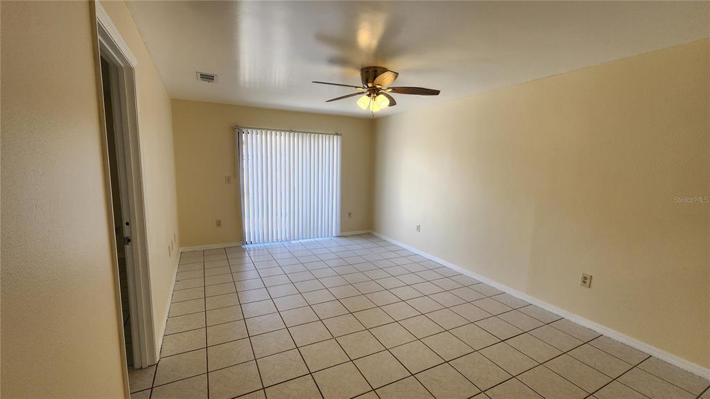An empty room with light-colored walls, tile flooring, a ceiling fan, and sliding glass doors — 2211 MARGARITA COURT UNIT 2211, KISSIMMEE, FL