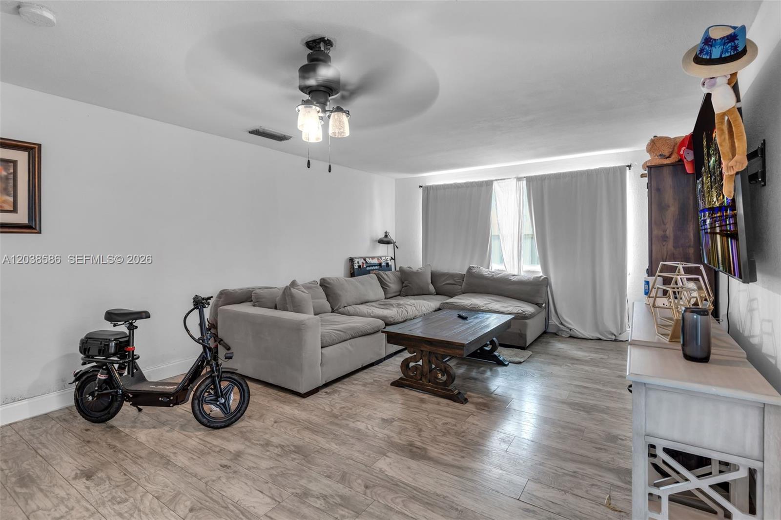 A living room features a grey sectional sofa, a wooden coffee table, and an electric scooter — 3510 SW 87th Ave, Miami FL 33165, MIAMI, FL