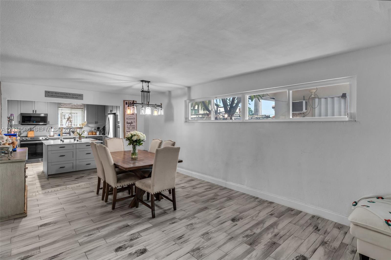 A dining area features a wooden table, upholstered chairs, a chandelier, and light wood-look flooring — 3510 SW 87th Ave, Miami FL 33165, MIAMI, FL