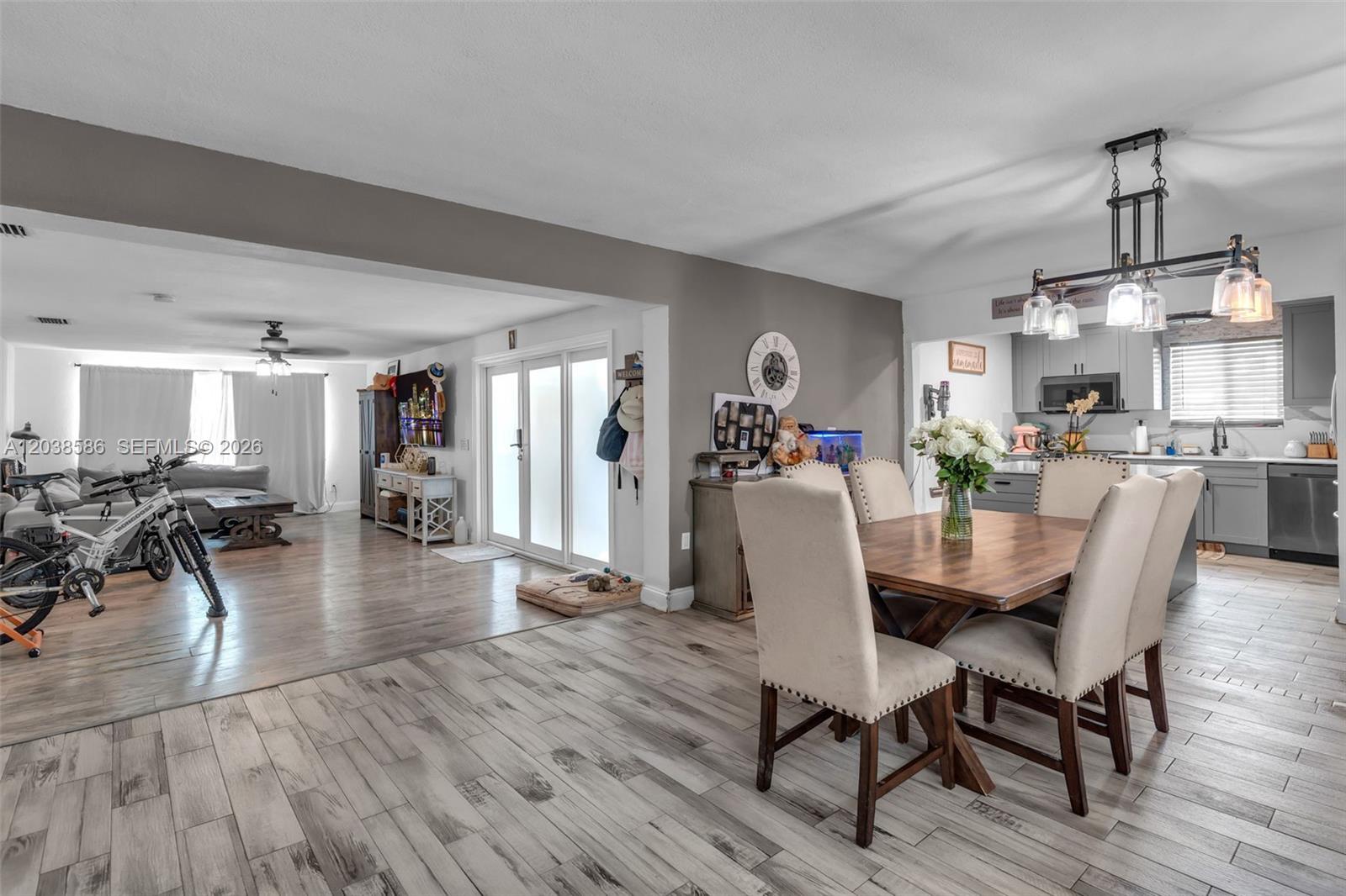 An open-concept dining area and living room with wood-look tile flooring and a modern chandelier — 3510 SW 87th Ave, Miami FL 33165, MIAMI, FL