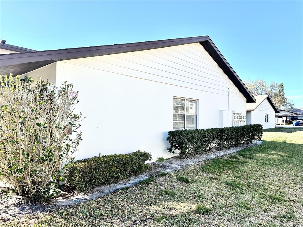 The exterior of a white building features a dark roof, a window, and landscaping — 2476 ENTERPRISE ROAD UNIT 6, CLEARWATER, FL