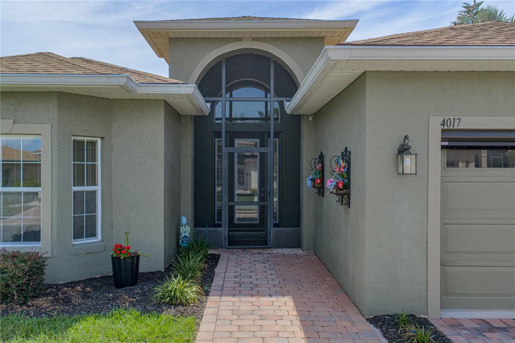 The exterior of a house features a brick walkway leading to a screened front entryway — 4017 DUNMORE DRIVE, LAKE WALES, FL