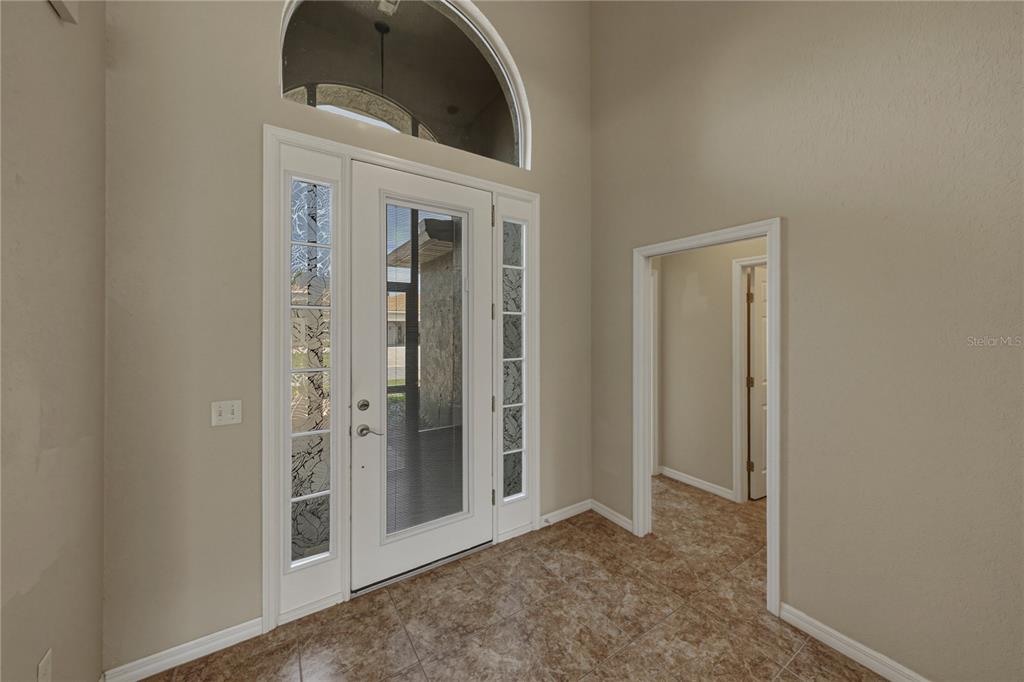 An entryway features a white front door with glass sidelights, a transom window, and tile flooring — 4017 DUNMORE DRIVE, LAKE WALES, FL
