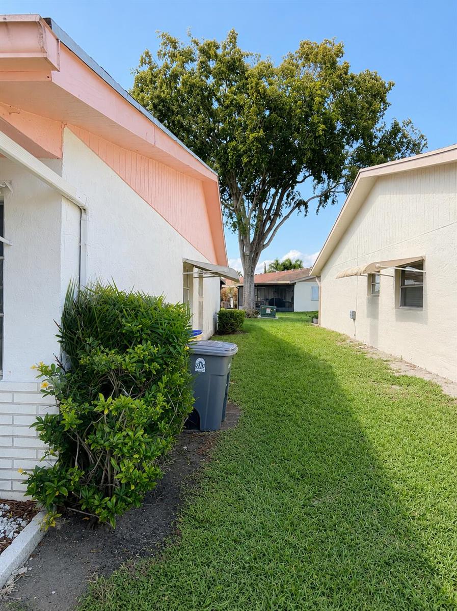 A narrow grassy side yard between two single-story houses with a large tree in back — 6069 La Palma Lane, Delray Beach FL 33484, DELRAY BEACH, FL