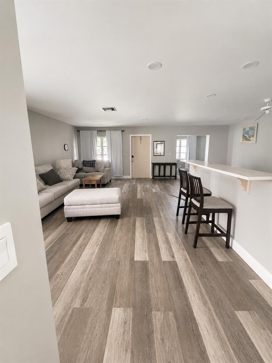 A living room with light gray walls, wood-look flooring, a sofa, and a breakfast bar — 6069 La Palma Lane, Delray Beach FL 33484, DELRAY BEACH, FL