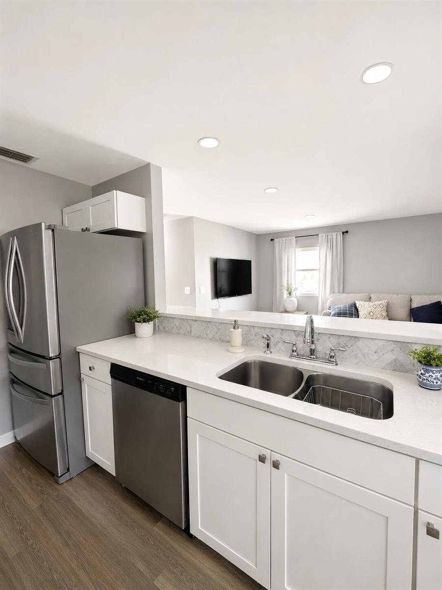 A kitchen with stainless steel appliances, white cabinets, and a view into the living room — 6069 La Palma Lane, Delray Beach FL 33484, DELRAY BEACH, FL