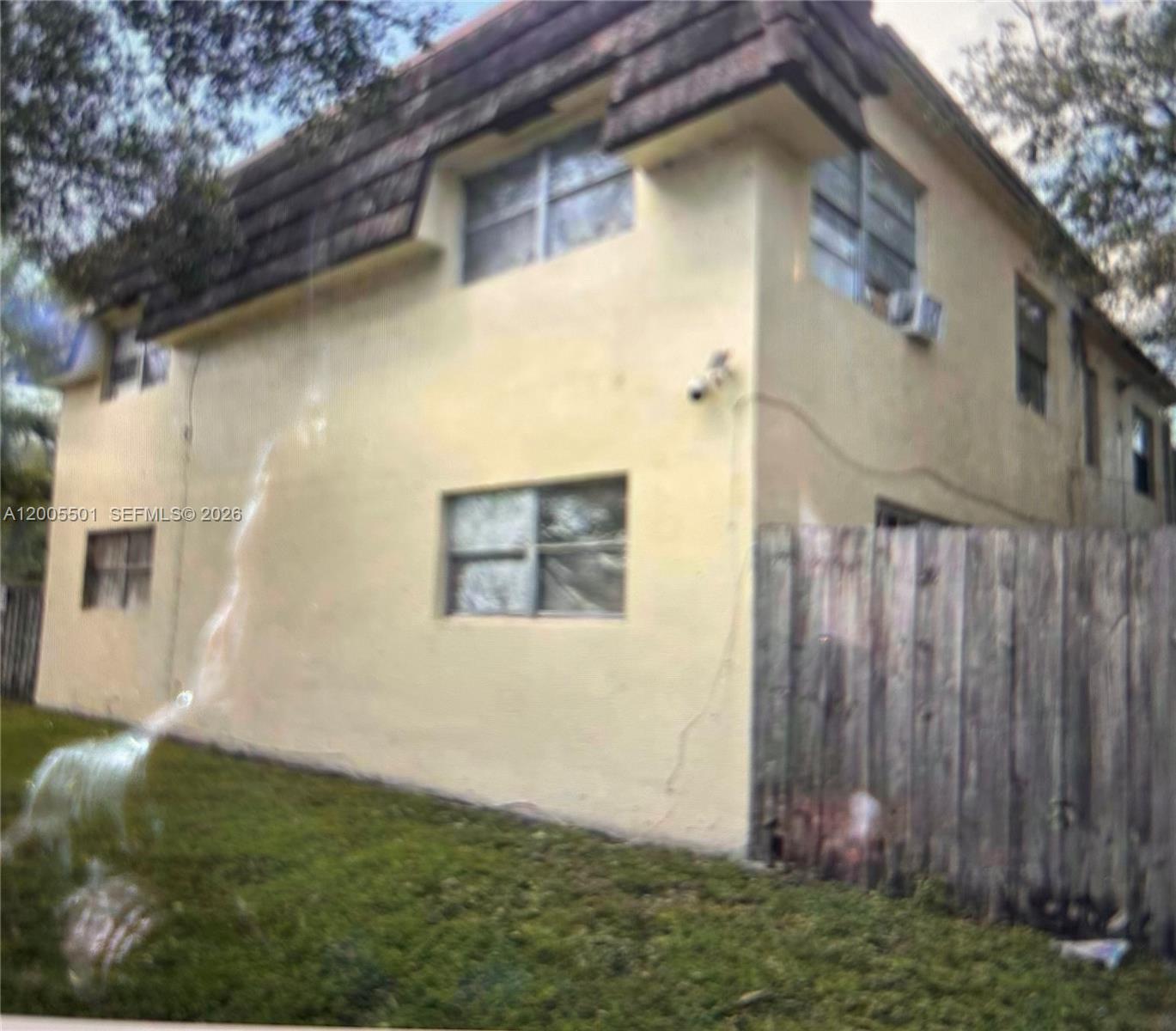 The exterior of a two-story stucco building with a wooden fence and grassy yard — 3820 SW 60th Ter # 1, Davie FL 33314, DAVIE, FL