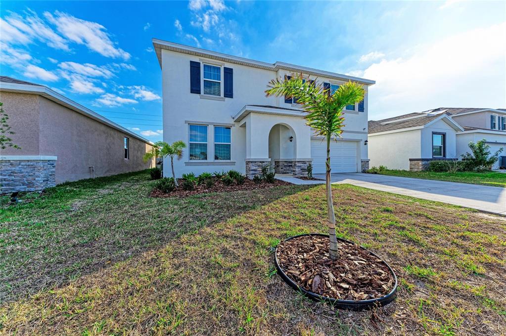 A two-story house with a white stucco facade, a front-facing garage, and a small palm tree — 3804 TURNING TIDES TERRACE, BRADENTON, FL
