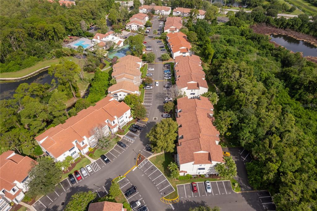 An aerial view shows multiple multi-story apartment buildings with orange roofs surrounded by lush greenery — 5124 CONROY ROAD UNIT 26, ORLANDO, FL
