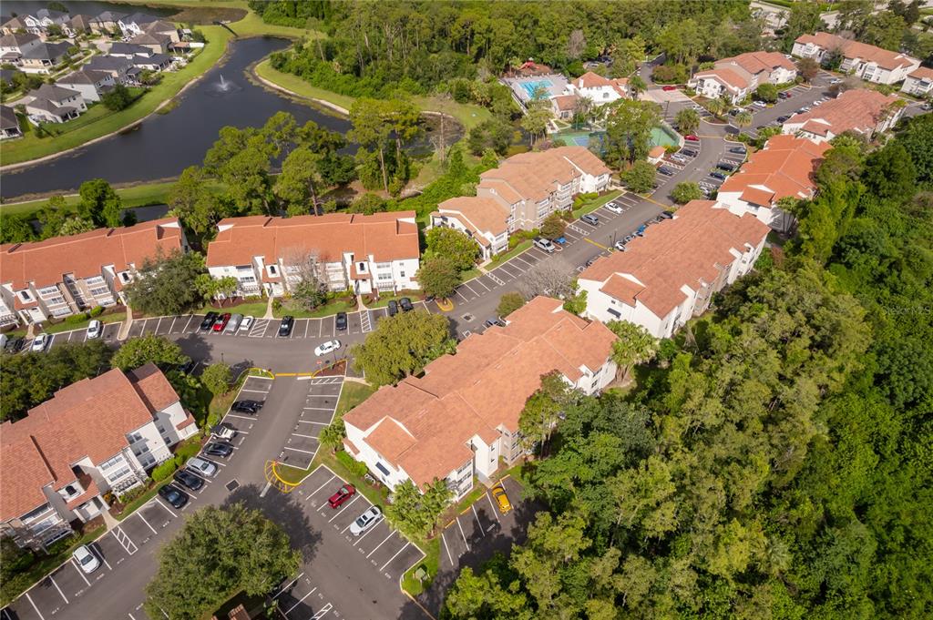 An aerial view shows multiple multi-story apartment buildings surrounded by parking lots and wooded areas — 5124 CONROY ROAD UNIT 26, ORLANDO, FL