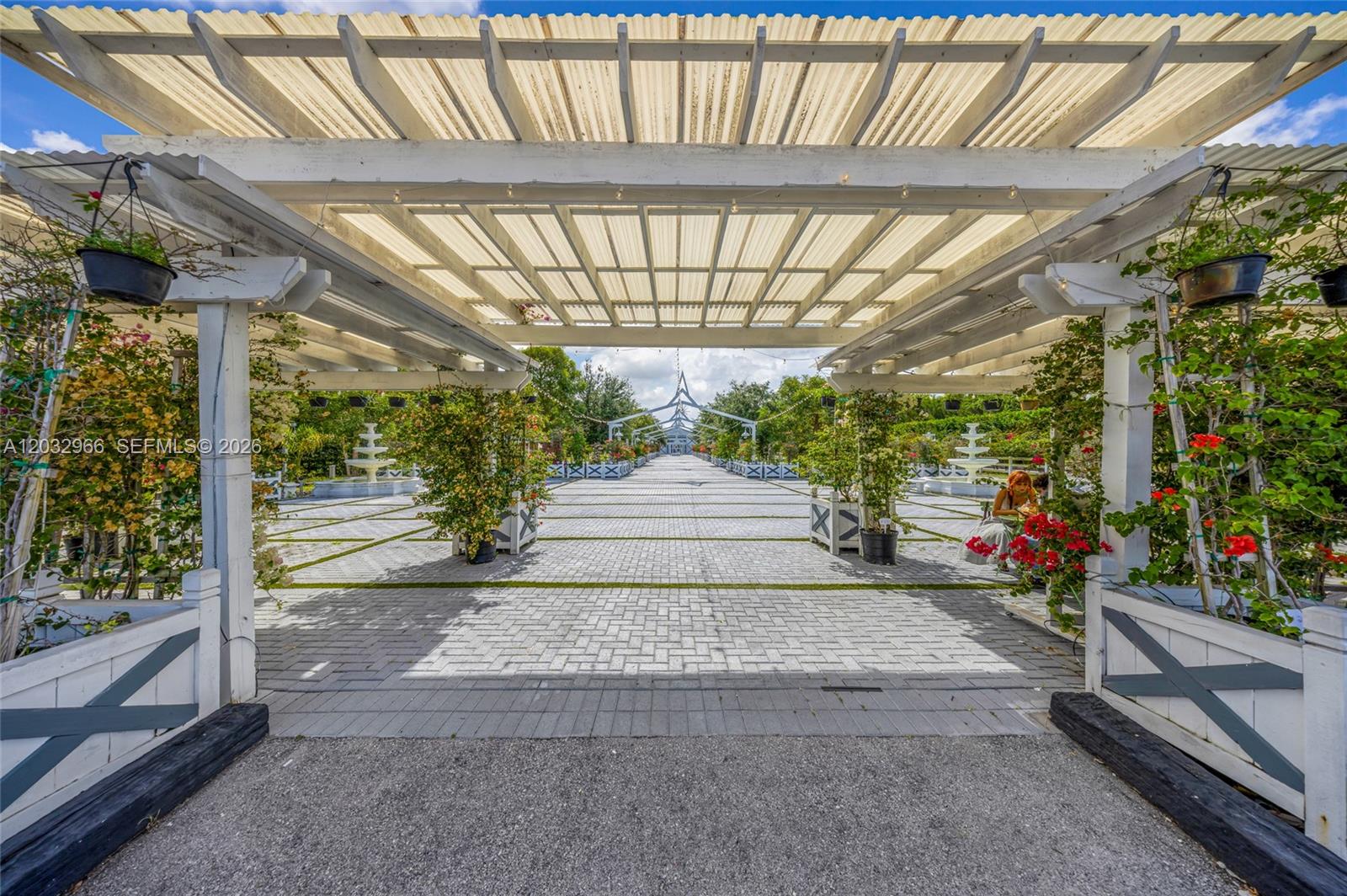 A paved outdoor walkway is covered by a white pergola with hanging potted plants — 4680 SW 148th Ave, Southwest Ranches FL 33330, SOUTHWEST RANCHES, FL