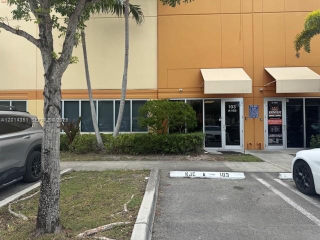 An exterior view of a commercial building with two glass-door entrances and parking spaces — 12601 NW 115th Ave # 103, Medley FL 33178, MEDLEY, FL
