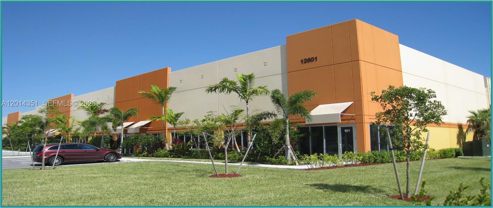 A low-rise commercial warehouse building features orange and beige panels with glass entry doors — 12601 NW 115th Ave # 103, Medley FL 33178, MEDLEY, FL