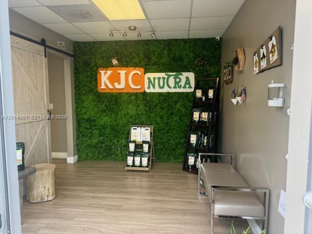 A retail space features a green moss wall with a KJC NUCRA sign and wood flooring — 12601 NW 115th Ave # 103, Medley FL 33178, MEDLEY, FL