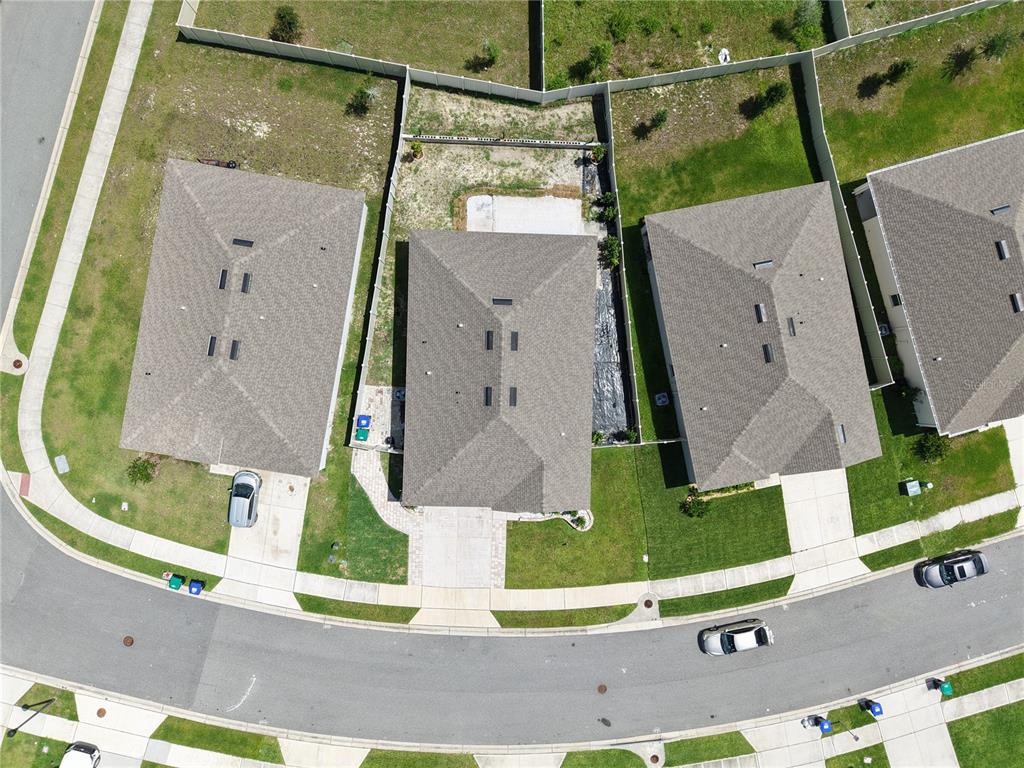 An aerial view shows three suburban houses with gray roofs and driveways along a curved street — 11370 AMBER RIDGE DRIVE, ZELLWOOD, FL