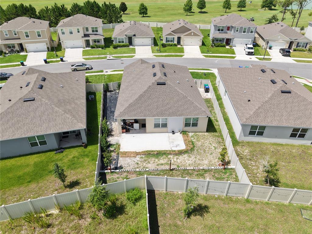 An aerial view shows the backyard and roof of a suburban house with a patio — 11370 AMBER RIDGE DRIVE, ZELLWOOD, FL