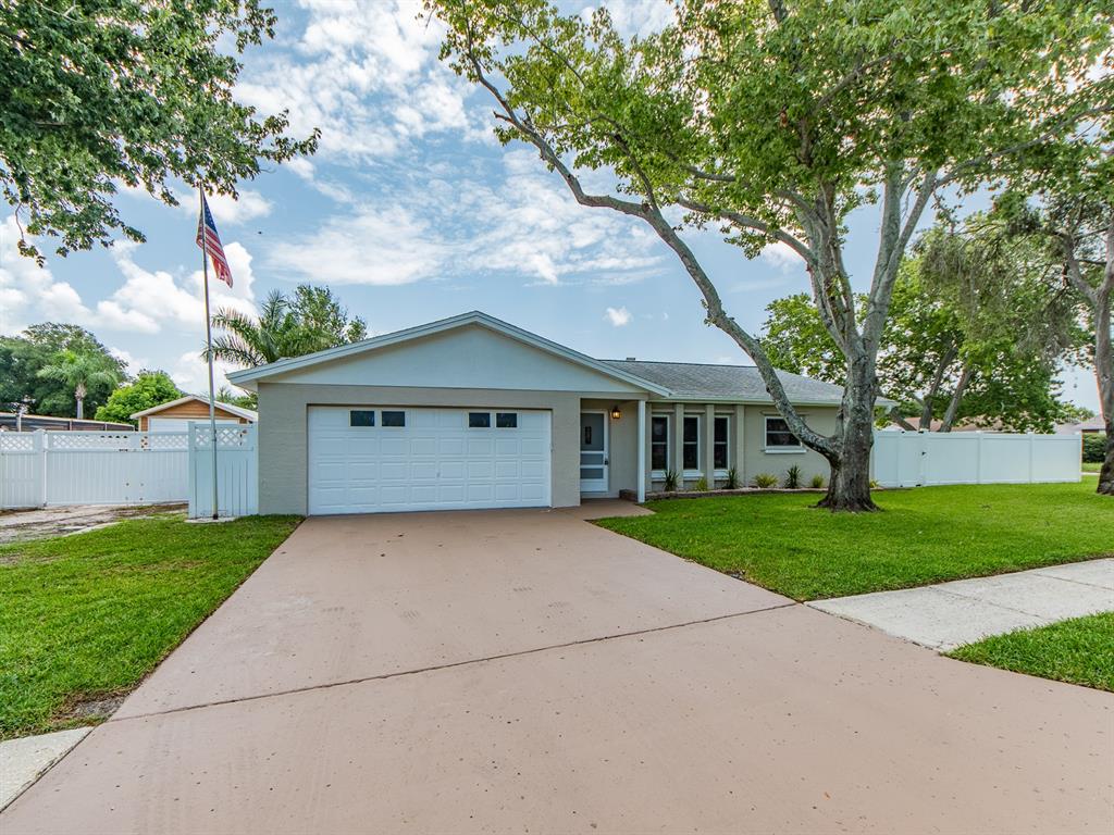 A single-story house with a two-car garage, a concrete driveway, and a large front tree — 11883 108TH AVENUE, LARGO, FL