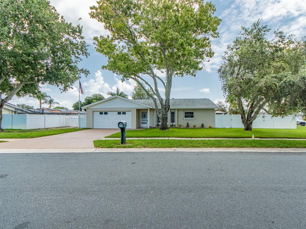A single-story house with a white garage, a large tree, and a white fence — 11883 108TH AVENUE, LARGO, FL