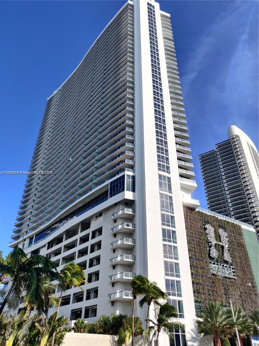A tall, white high-rise building features numerous balconies and a large vertical green wall sign — 4111 S Ocean Dr # 1506, Hollywood FL 33019, HOLLYWOOD, FL