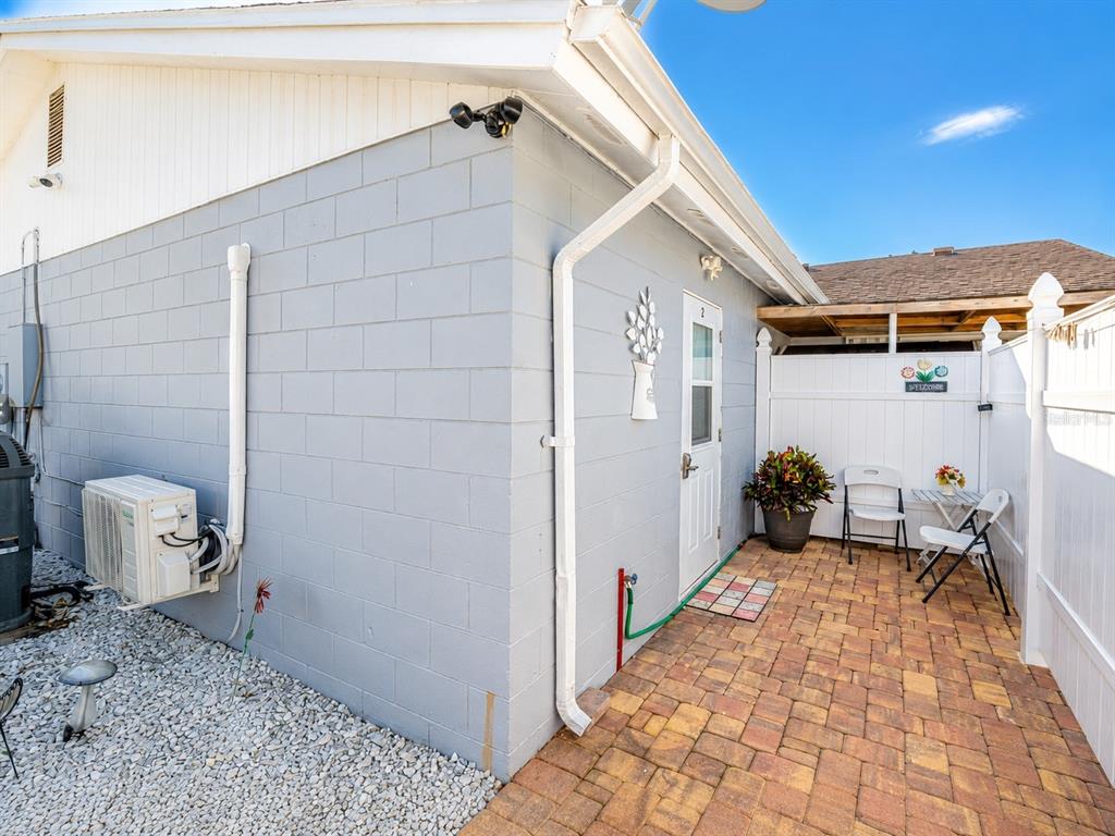 A gray concrete block exterior wall features a white door, a patio, and outdoor seating — 111 CUAUTLA WAY UNIT 2, KISSIMMEE, FL