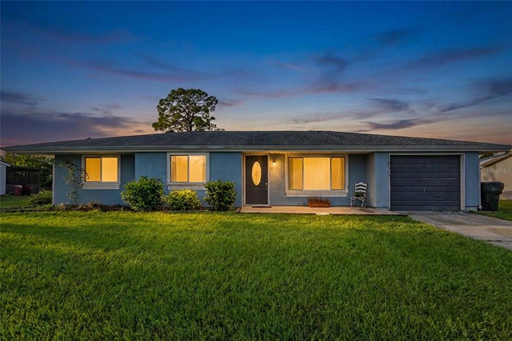 A single-story blue house with a garage and a large front lawn at dusk — 6703 ELECTRA AVENUE, NORTH PORT, FL
