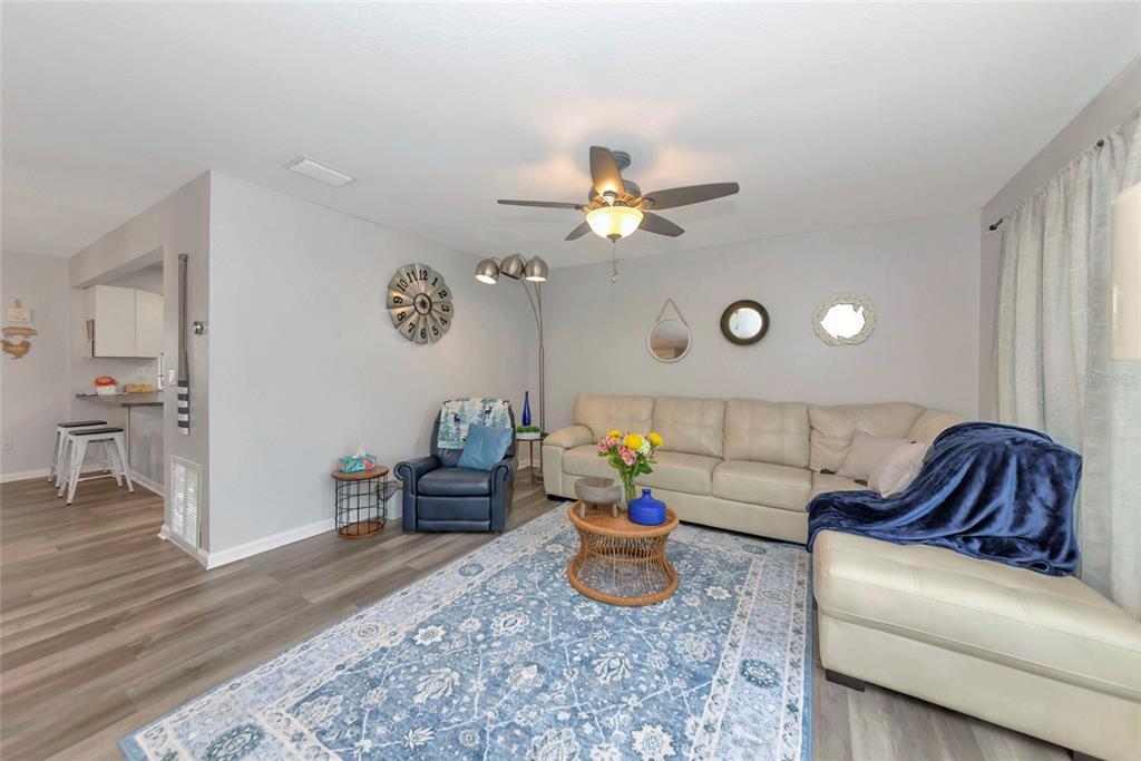 A living room features a beige sectional sofa, a blue armchair, and a patterned rug — 6703 ELECTRA AVENUE, NORTH PORT, FL