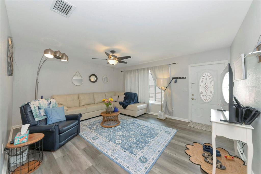 A living room features a sectional sofa, blue armchair, area rug, and front entry door — 6703 ELECTRA AVENUE, NORTH PORT, FL