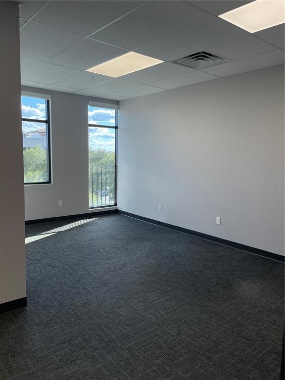 An empty office space features gray carpet, white walls, and two windows with exterior views — 13550 VILLAGE PARK DRIVE UNIT 345, ORLANDO, FL