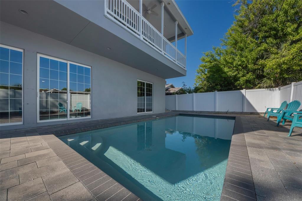 A rectangular swimming pool sits on a paved patio beside a two-story gray house — 3120 CLINTON STREET S, GULFPORT, FL