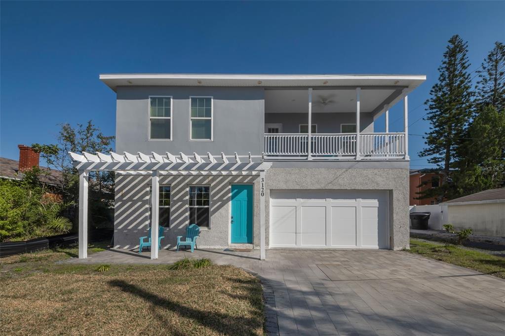 A two-story gray house features a white pergola, a turquoise front door, and an upper balcony — 3120 CLINTON STREET S, GULFPORT, FL