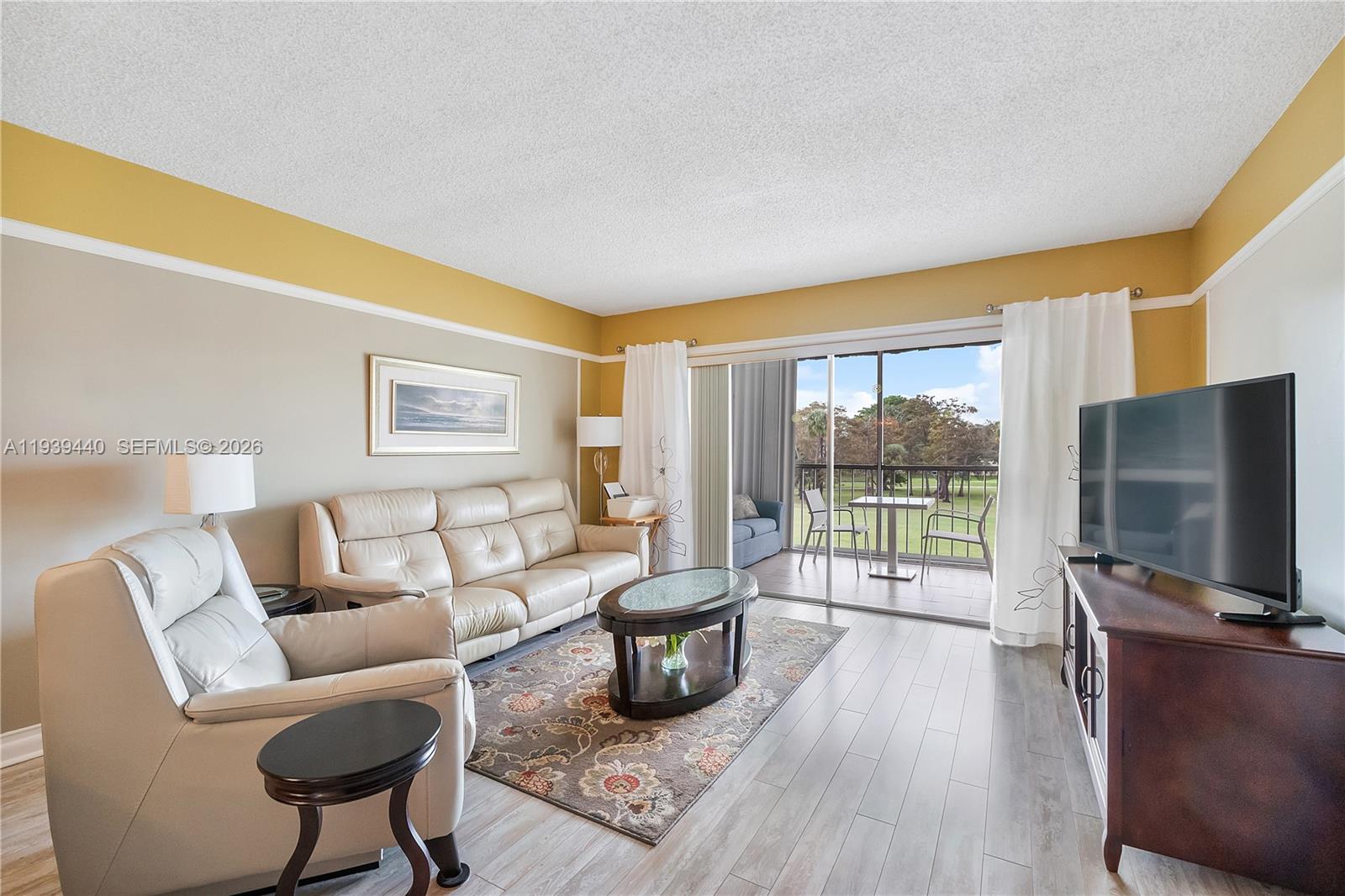 A living room features light-colored leather furniture, a patterned rug, and a sliding glass door — 7847 Golf Circle Dr # 309, Margate FL 33063, MARGATE, FL