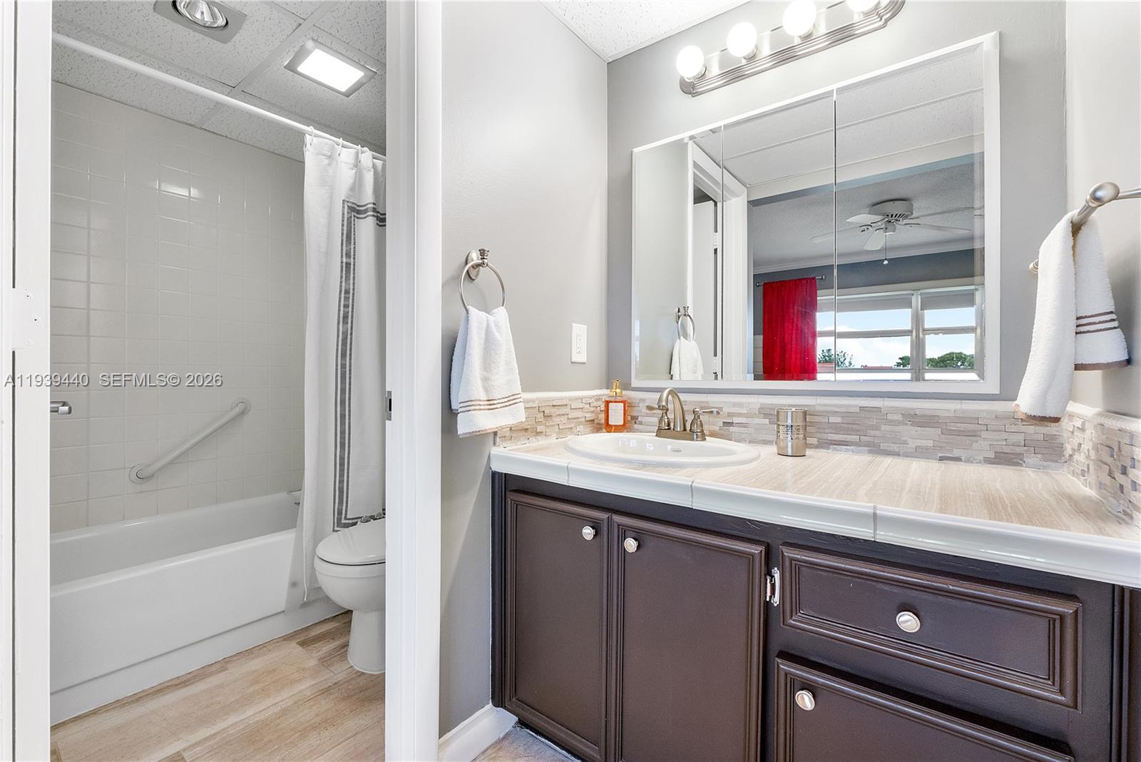 A bathroom features a dark wood vanity, a tiled backsplash, and a separate tub area — 7847 Golf Circle Dr # 309, Margate FL 33063, MARGATE, FL
