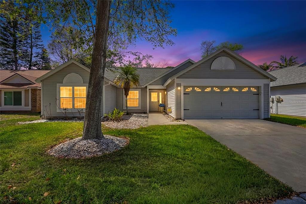 A single-story house with gray siding, a two-car garage, and a front lawn at dusk — 1640 COUNTRYWOOD STREET, TARPON SPRINGS, FL