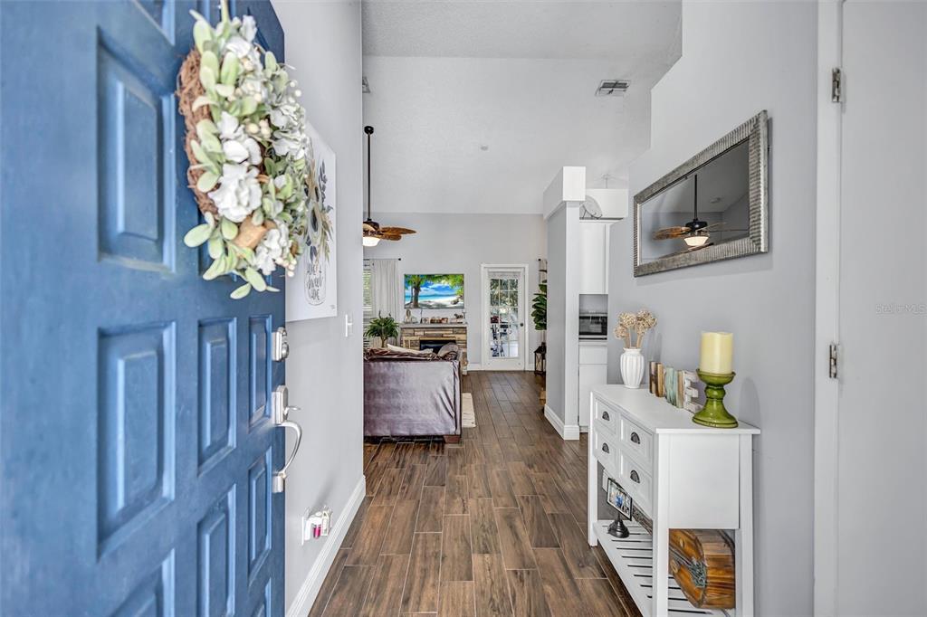 An entryway with a blue door leads into a living room with wood-look tile flooring — 1640 COUNTRYWOOD STREET, TARPON SPRINGS, FL