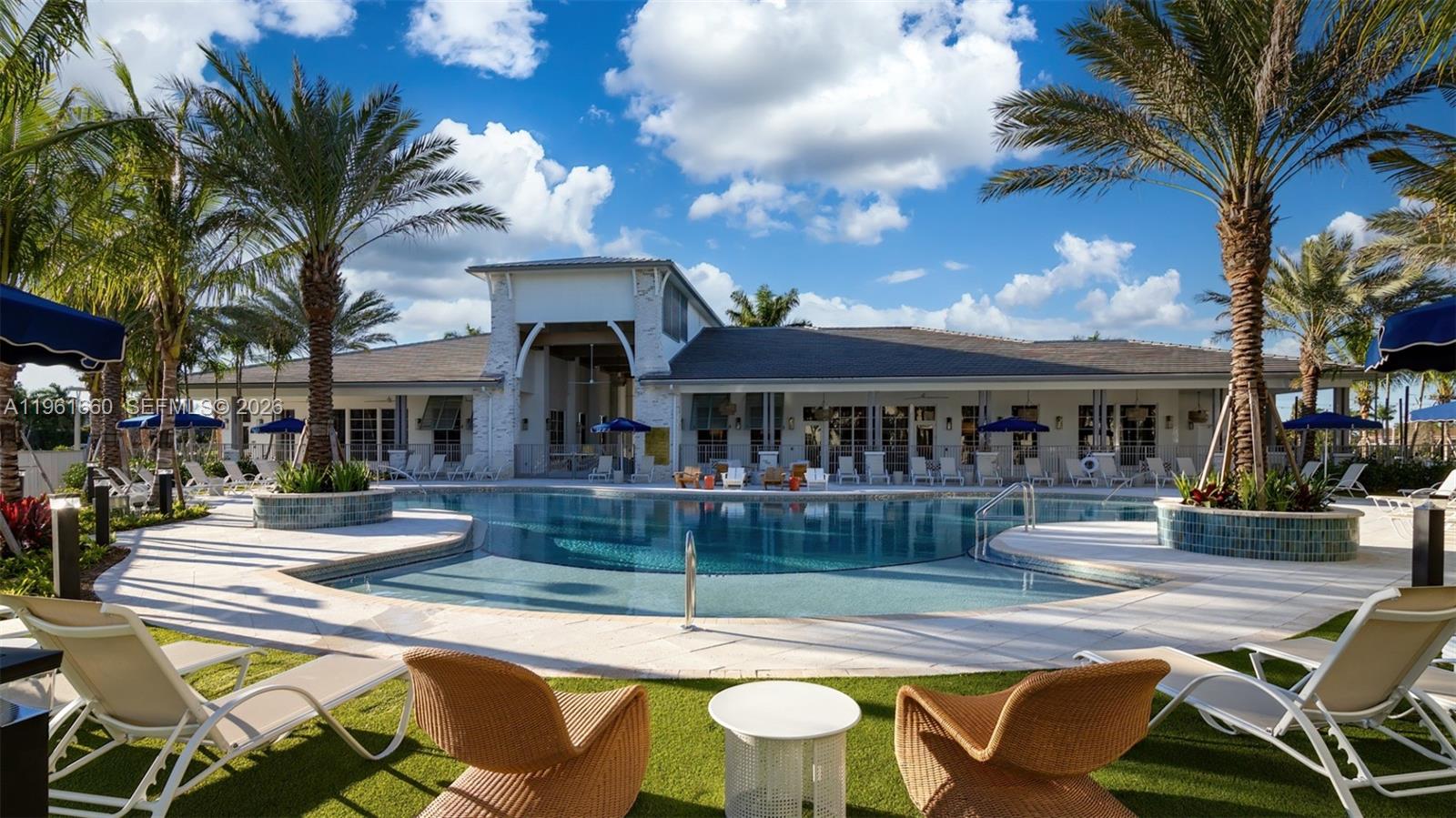 A swimming pool sits in front of a clubhouse building with palm trees and lounge chairs — 4310 Chukka Ln # A1, Lake Worth FL 33467, LAKE WORTH, FL