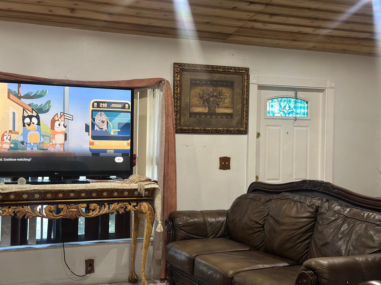 A living room features a television on an ornate table, a leather sofa, and door — 5654 E Ithaca Cir Circle E, Lake Worth FL 33463, LAKE WORTH, FL