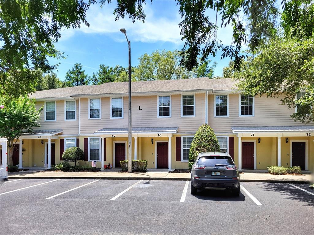 A two-story apartment building with tan siding, red shutters, and numbered front doors — 2508 SW 35TH PLACE UNIT 70, GAINESVILLE, FL