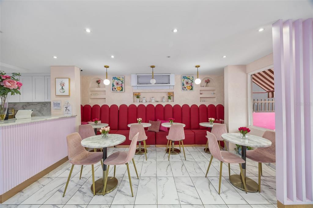 A cafe interior features pink velvet banquette seating, marble-topped tables, and pink upholstered chairs — 156 WINSTON CHURCHILL AVENUE, SAN JUAN, PR