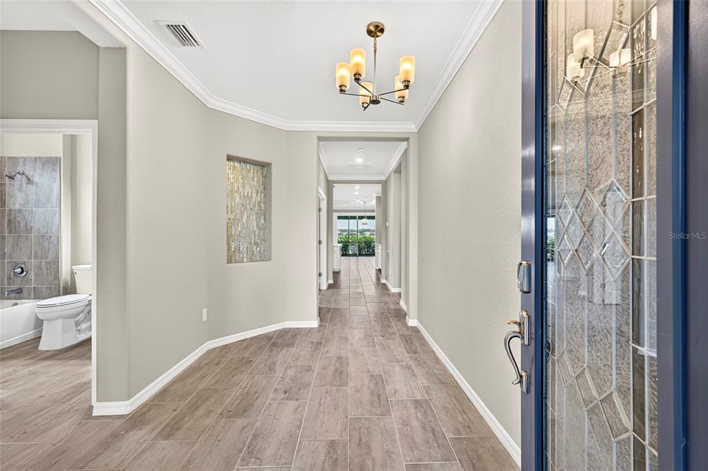 A foyer with wood-look tile flooring leads to a hallway with a decorative wall niche — 16279 BONITA LANDING CIRCLE, BONITA SPRINGS, FL