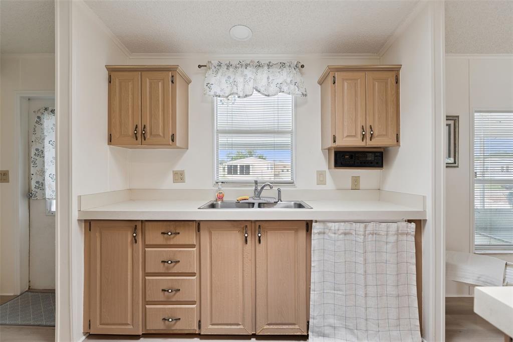 A kitchen features light wood cabinets, a double sink, and a window with a valance — 523 NESBITT PARK AVENUE, DAVENPORT, FL