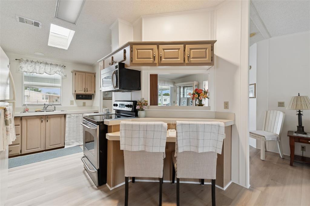 A kitchen features light wood cabinets, a breakfast bar with two chairs, and stainless appliances — 523 NESBITT PARK AVENUE, DAVENPORT, FL