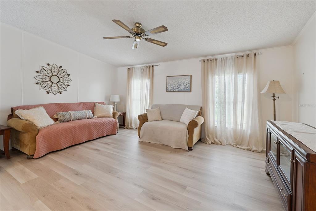 A living room features light wood flooring, two sofas, a ceiling fan, and sheer curtains — 523 NESBITT PARK AVENUE, DAVENPORT, FL